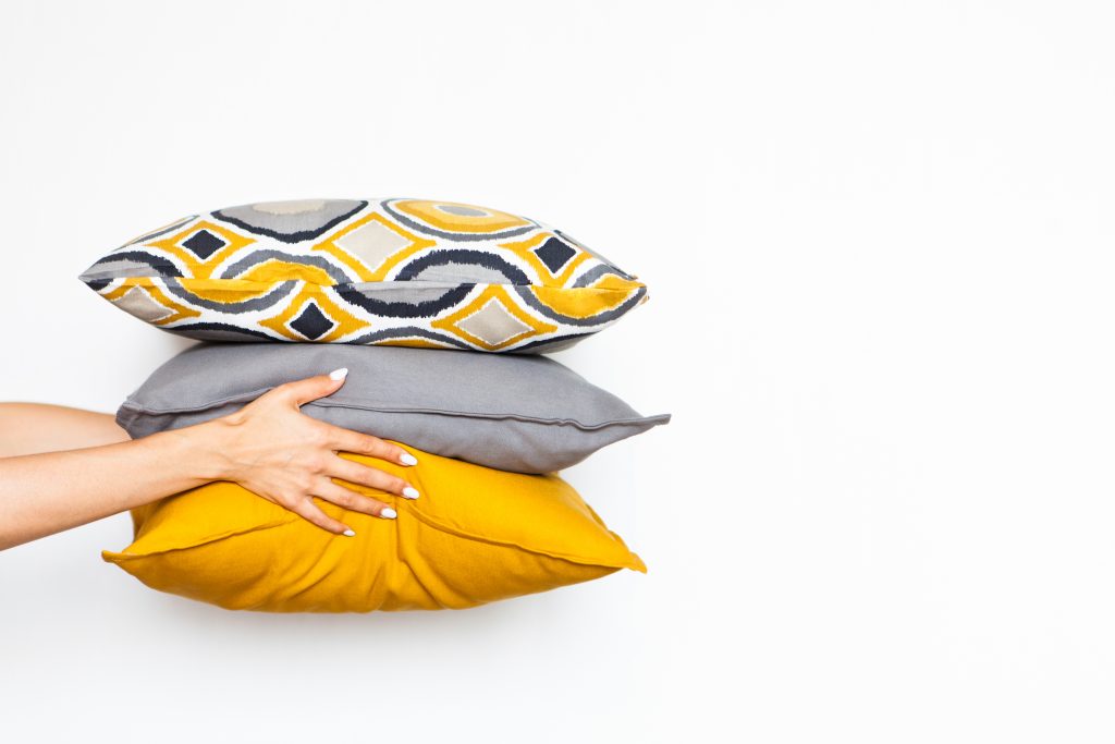 Colorful pillows in women's hands on a white isolated background, the concept of home comfort6 close up, copy space
